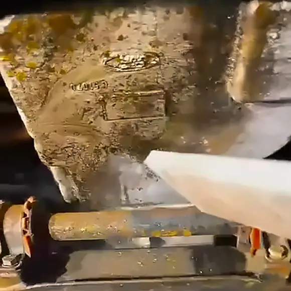 A casing under the Ford covered in grime and old underseal, the Ford badge barely visible, as the dry ice nozzle starts on it.